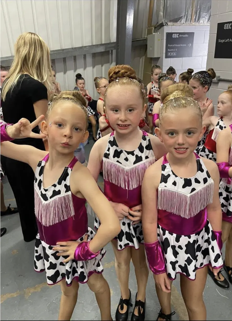 Group of dancers in cow print costumes backstage