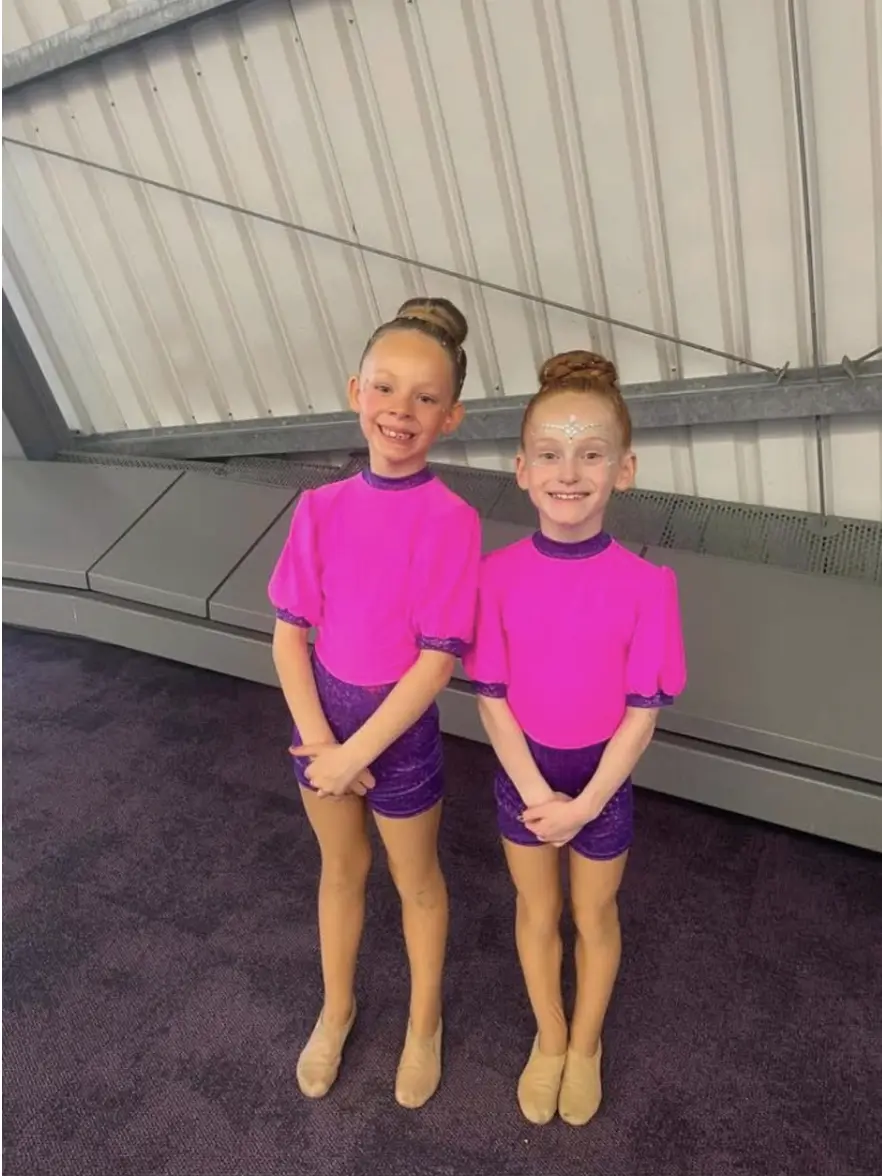 Two dancers in pink and purple costumes side by side